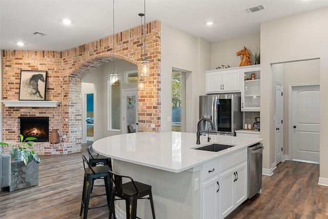 925 Overstreet Ln, Leander, TX 78641 - kitchen with stainless steel appliances, a sink, dark wood finished floors, open floor plan, and a brick fireplace