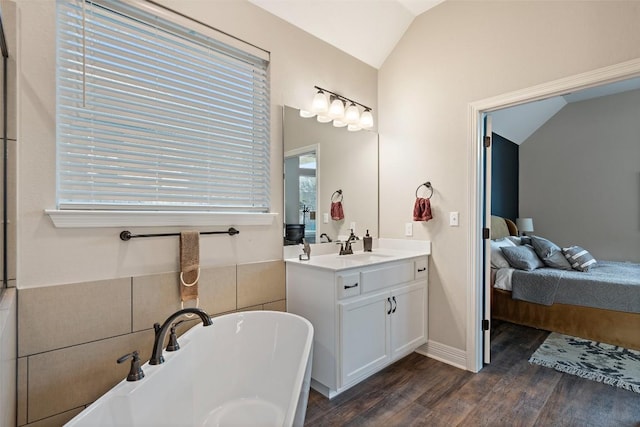 925 Overstreet Ln, Leander, TX 78641 - ensuite bathroom with lofted ceiling, wood finished floors, a freestanding bath, vanity, and baseboards