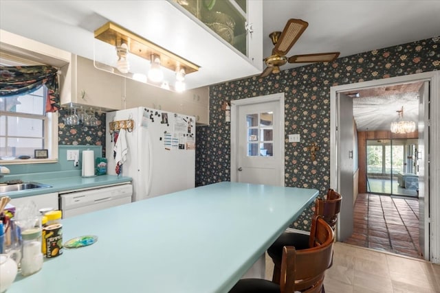 kitchen featuring sink, white cabinetry, ceiling fan with notable chandelier, and white appliances