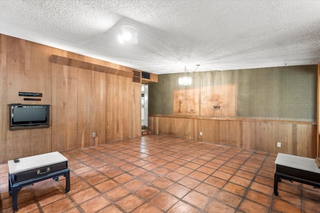 basement featuring tile patterned flooring, a textured ceiling, and wooden walls