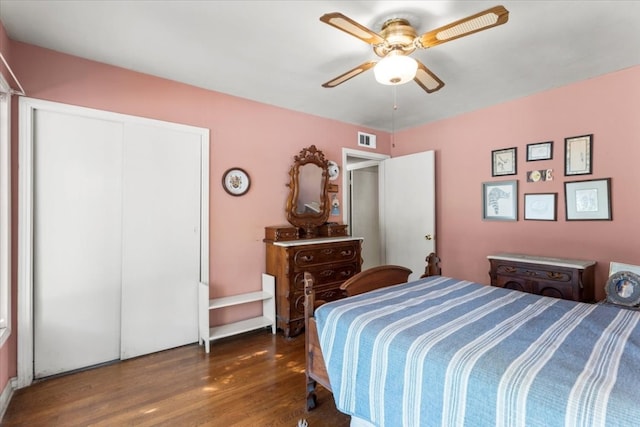 bedroom with a closet, dark hardwood / wood-style floors, and ceiling fan