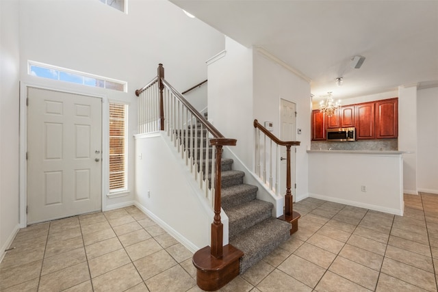 entrance foyer with a high ceiling, light tile patterned flooring, and a notable chandelier