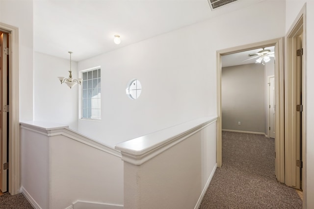 hallway featuring dark colored carpet and a chandelier