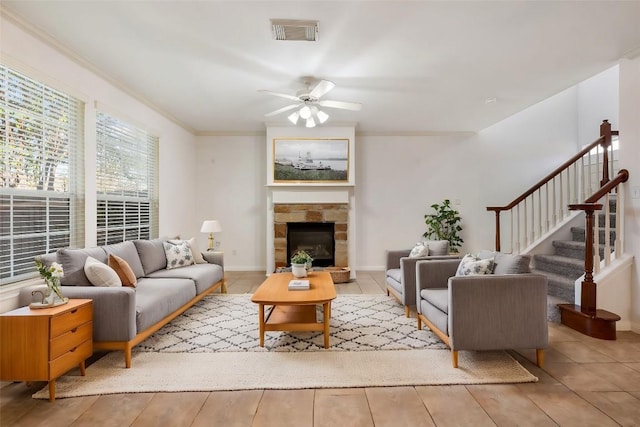 living room with crown molding, ceiling fan, and a fireplace