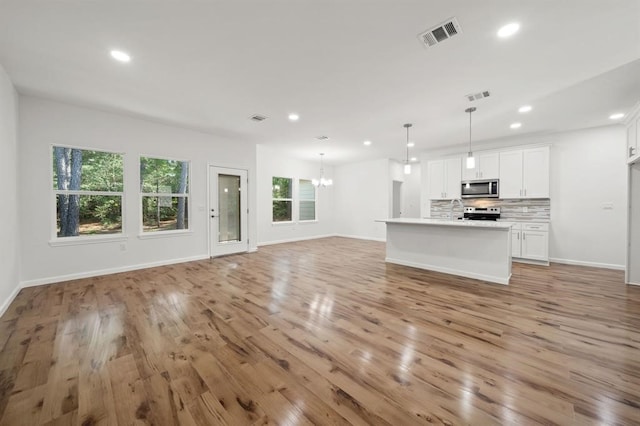 unfurnished living room with a chandelier, sink, and light wood-type flooring