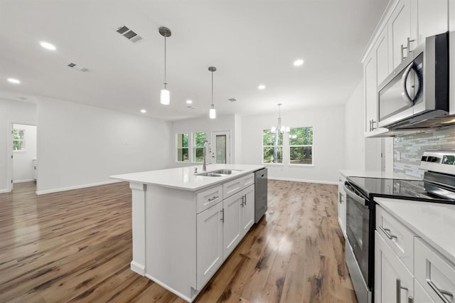 kitchen with appliances with stainless steel finishes, white cabinetry, a kitchen island with sink, and plenty of natural light