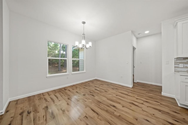 unfurnished dining area with an inviting chandelier and light hardwood / wood-style flooring