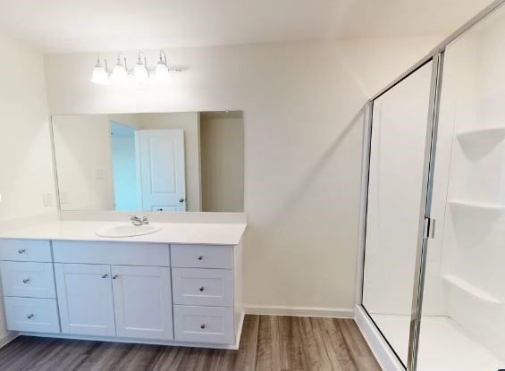 bathroom with a shower with door, vanity, and hardwood / wood-style flooring