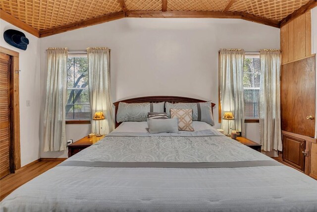 bedroom featuring multiple windows, wood finished floors, and lofted ceiling