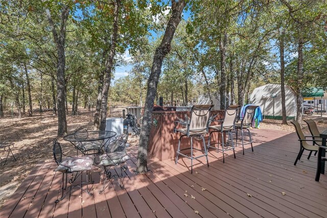 deck with an outdoor structure, outdoor dining area, and a storage unit