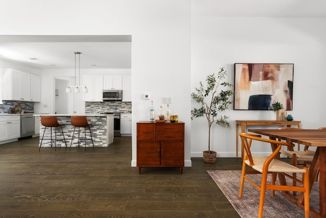 kitchen with backsplash, a kitchen bar, decorative light fixtures, white cabinetry, and appliances with stainless steel finishes