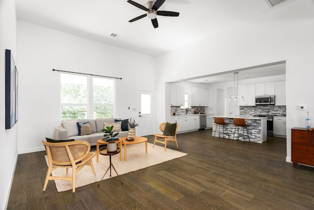 living room featuring ceiling fan, a towering ceiling, and dark hardwood / wood-style flooring