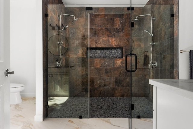 bathroom featuring vanity, a shower with shower door, and toilet