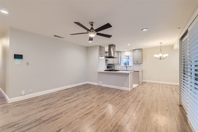 kitchen with light hardwood / wood-style flooring, backsplash, island range hood, and kitchen peninsula