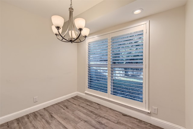 empty room with hardwood / wood-style flooring and a chandelier