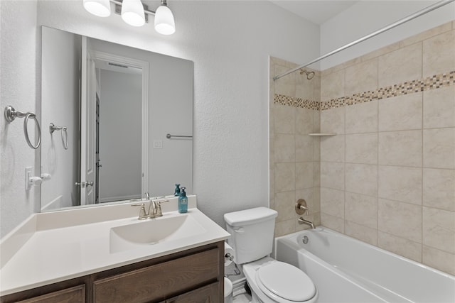 full bathroom featuring vanity, tiled shower / bath combo, and toilet