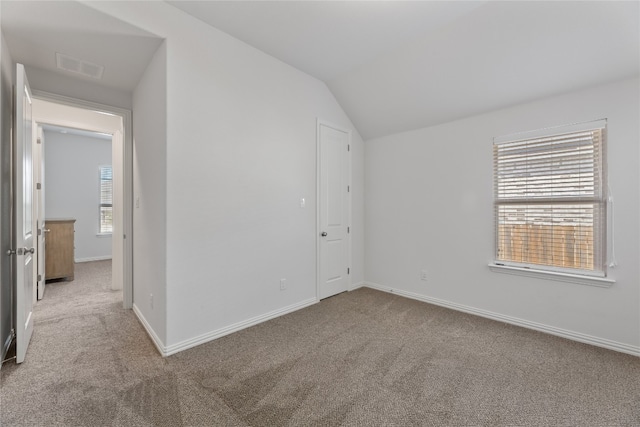 carpeted empty room featuring lofted ceiling