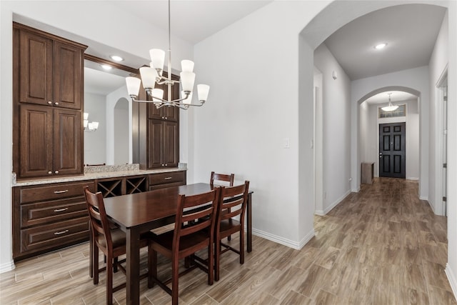 dining area with light wood-type flooring and an inviting chandelier