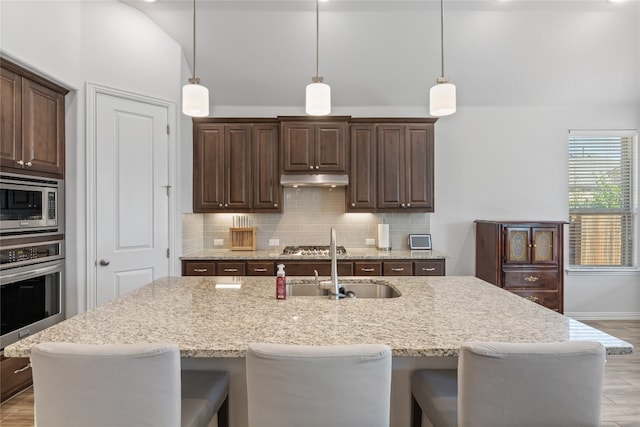 kitchen featuring dark brown cabinets, an island with sink, and appliances with stainless steel finishes