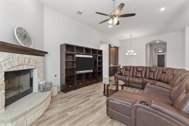 living room with a fireplace, ceiling fan with notable chandelier, and light hardwood / wood-style floors