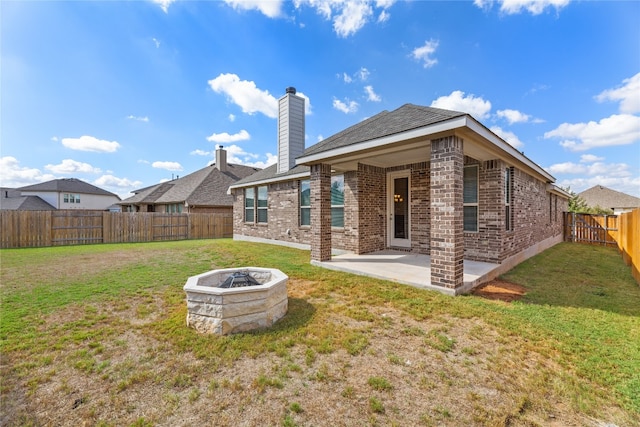 back of property with a patio, a fire pit, and a lawn