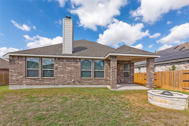 rear view of property with a yard, a fire pit, and a patio area