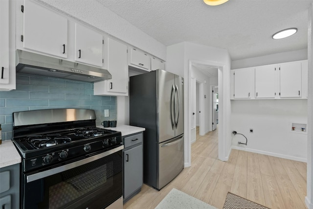 kitchen with white cabinets, stainless steel appliances, light wood-type flooring, and backsplash