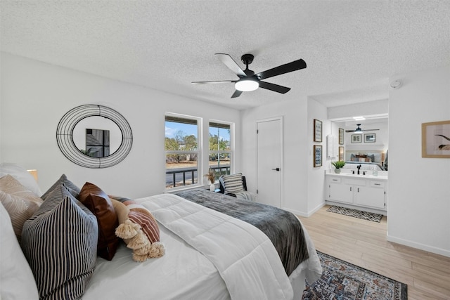 bedroom with ceiling fan, a textured ceiling, light hardwood / wood-style flooring, and ensuite bathroom