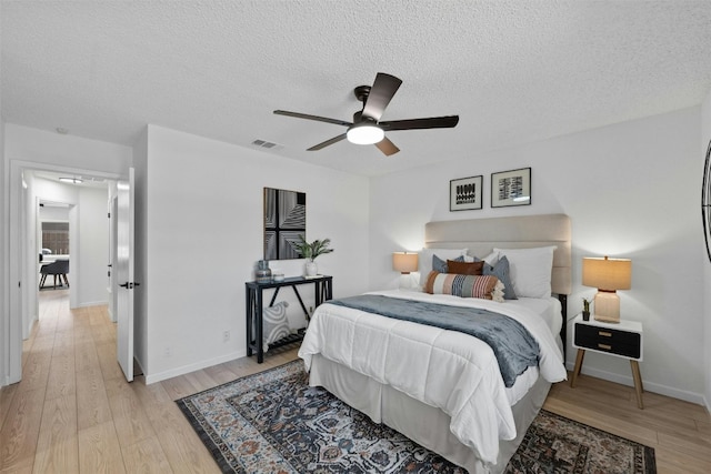 bedroom with light hardwood / wood-style flooring, a textured ceiling, and ceiling fan