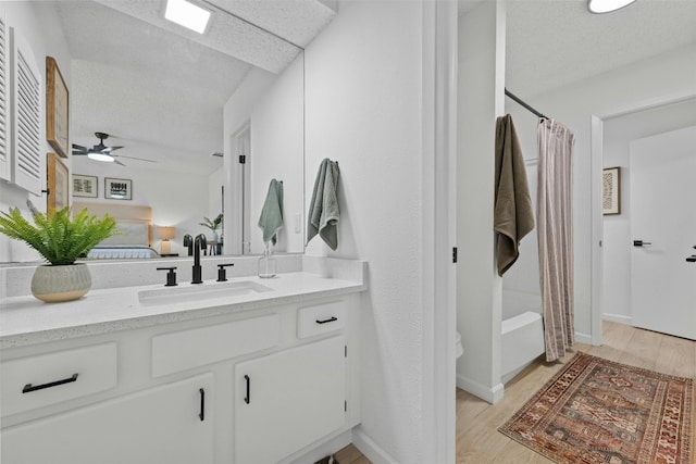 full bathroom featuring vanity, hardwood / wood-style floors, shower / tub combo with curtain, and ceiling fan