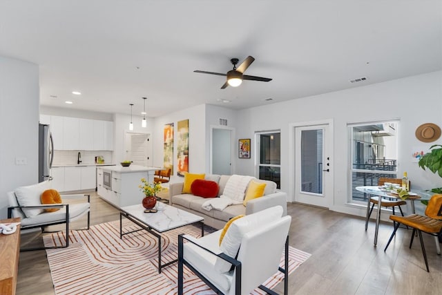 living room with ceiling fan, sink, and light hardwood / wood-style flooring