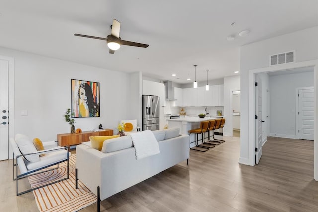 living room featuring light wood-type flooring and ceiling fan