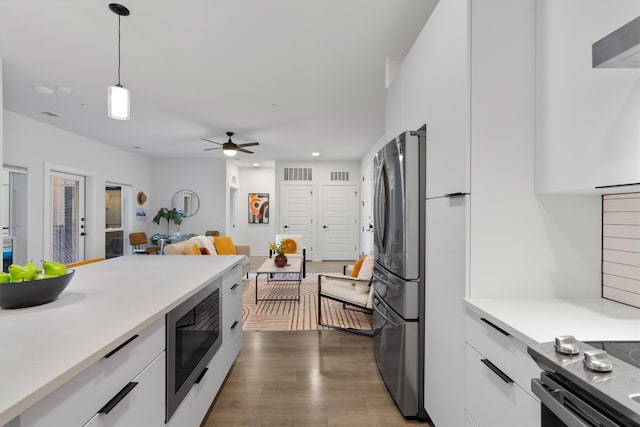 kitchen featuring stainless steel refrigerator, built in microwave, dark wood-type flooring, pendant lighting, and white cabinets