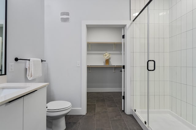 bathroom featuring tile patterned flooring, vanity, toilet, and a shower with shower door