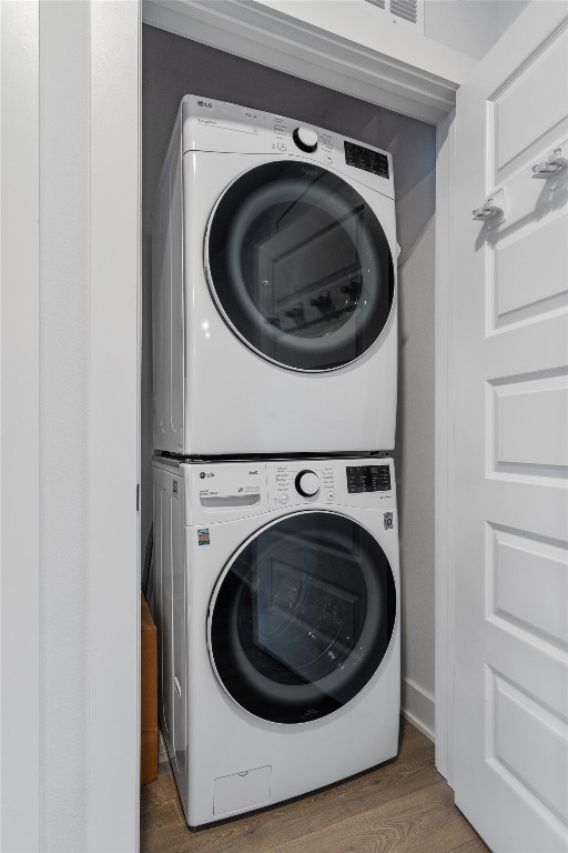 washroom featuring stacked washer / drying machine and dark hardwood / wood-style floors