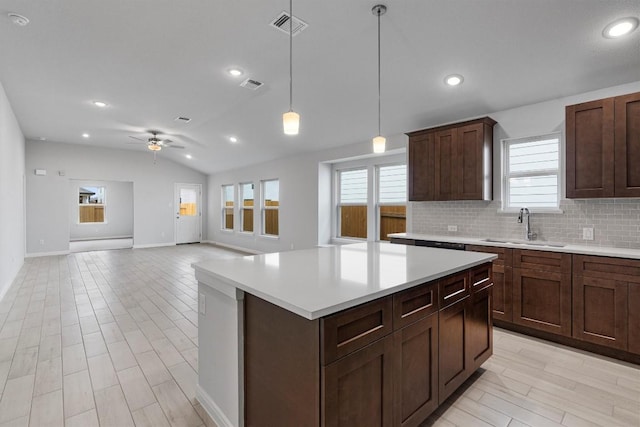 kitchen featuring ceiling fan, sink, lofted ceiling, decorative light fixtures, and a kitchen island