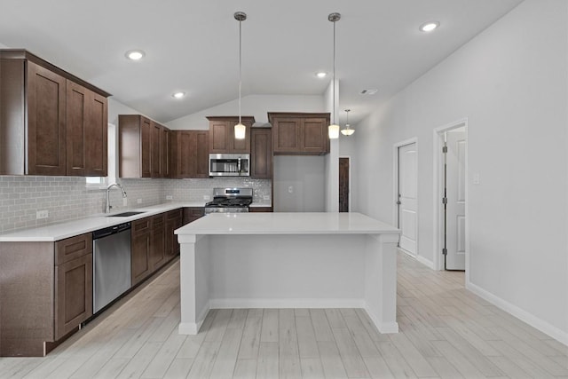 kitchen featuring dark brown cabinetry, stainless steel appliances, pendant lighting, decorative backsplash, and a kitchen island