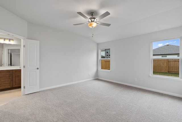 unfurnished bedroom with light carpet, ensuite bathroom, vaulted ceiling, and ceiling fan