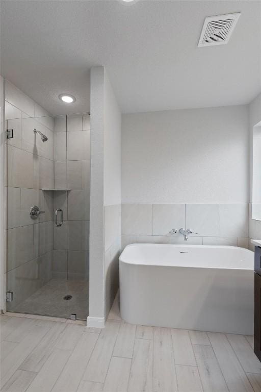 bathroom with vanity, tile walls, and plus walk in shower