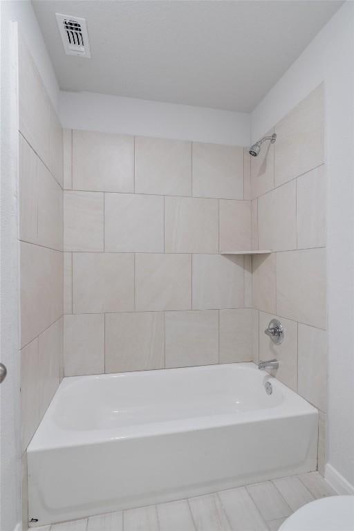 bathroom with tiled shower / bath combo and toilet