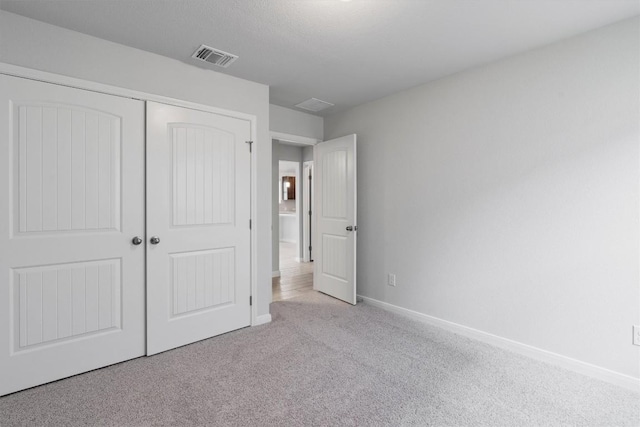 unfurnished bedroom featuring light carpet and a closet