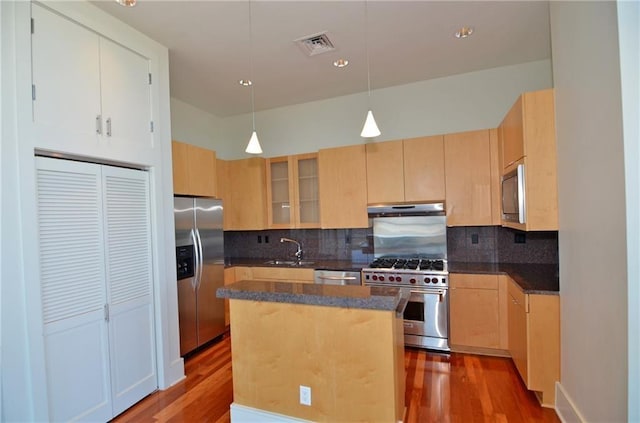 kitchen featuring hanging light fixtures, hardwood / wood-style floors, a kitchen island, and stainless steel appliances