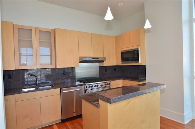 kitchen with a center island, light brown cabinets, sink, decorative light fixtures, and stainless steel appliances