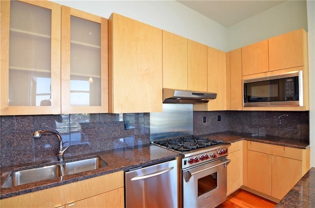 kitchen with light brown cabinets, sink, decorative backsplash, dark stone countertops, and appliances with stainless steel finishes