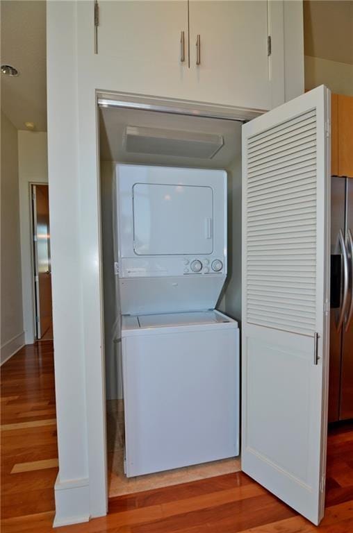 clothes washing area featuring stacked washer / drying machine and light hardwood / wood-style floors