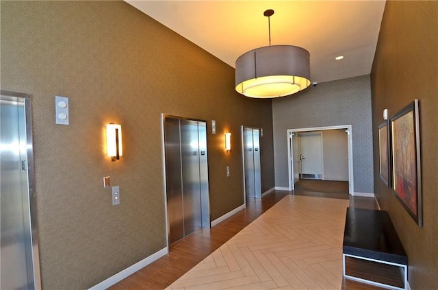 corridor featuring elevator and high vaulted ceiling