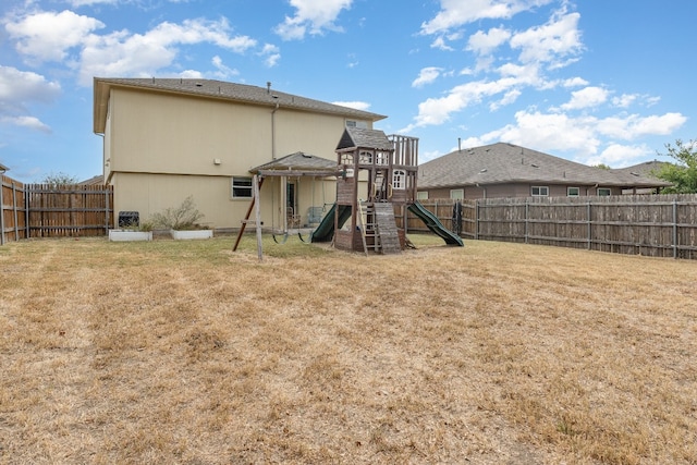 back of house with a playground and a lawn