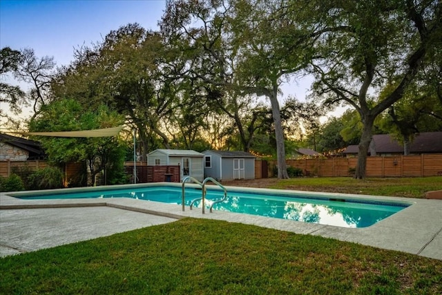view of pool featuring a yard, a fenced in pool, an outdoor structure, a patio, and a fenced backyard