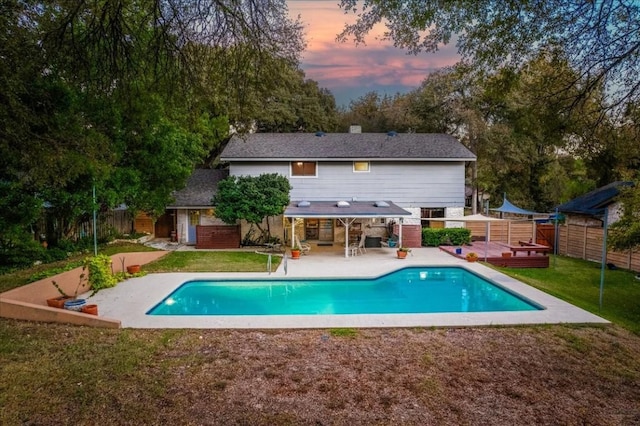 outdoor pool featuring an outbuilding, a deck, a fenced backyard, a yard, and a patio area