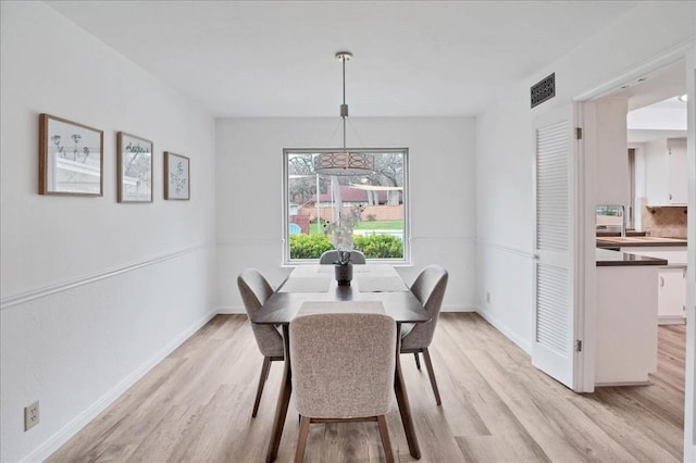 dining area with light wood finished floors, visible vents, and baseboards